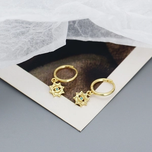 Detailed close-up of golden evil eye hoop earrings with a sparkling blue gemstone inlay