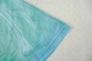 Detailed close-up of blue and green mesh fabric with dye print and neat stitching