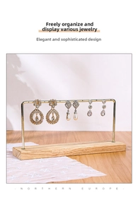 Detail view of gold metal earring holder with holes and natural wooden base