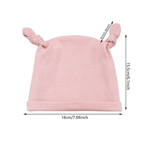 Bonnet en tricot rose pour bébé avec nœuds et bois, affichant les dimensions de la taille