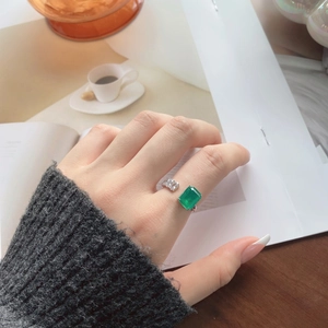 Macro shot of S925 emerald ring with rectangle gemstone worn on a hand in a cozy cafe