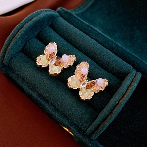 Close-up of 3D butterfly earrings with colorful crystals on a green velvet jewelry box