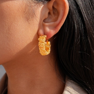 Détail de boucles d'oreilles géométriques plaquées or 24 carats portées par un mannequin