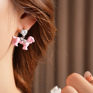 Pink dog stud earring with heart diamond and silver bow detail on model's ear