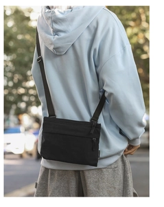 Rear view of a minimalist black nylon crossbody bag showing its multi-layered design