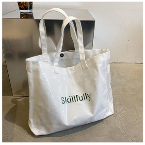 Close-up of a white tote bag with glossy finish and green Skillfully text detail