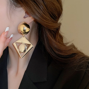 Detailed view of oversized golden geometric drop earrings with hollow diamond shape