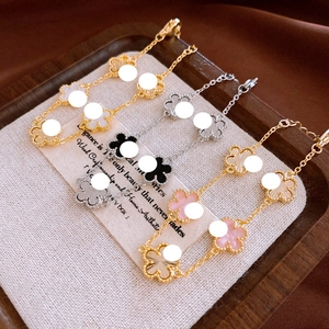 Detailed macro view of gold-plated clover bracelets with white mother of pearl and enamel