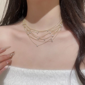 Detail of layered gold necklace with round cubic zirconia pendants on model's neck