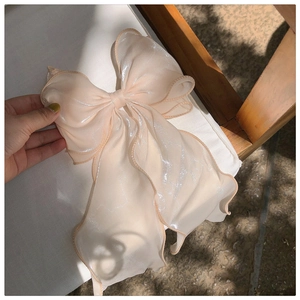 Macro shot of an oversized beige iridescent organza bow hairclip with shimmering details