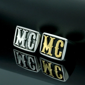 Detail of square punk rings with MC lettering in silver and gold on a mirror base