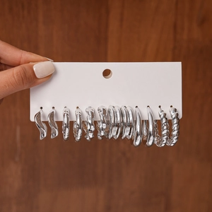 Detail view of 6 pairs of silver geometric hoop earrings on a display card with various textures