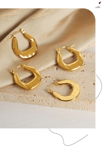 Detailed macro view of four U-shaped gold plated earrings on stone with silk fabric