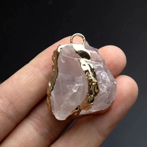 Close-up of a raw rose quartz pendant featuring an electroplated gold edge finish