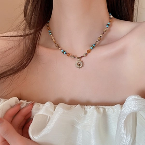 Detail of colorful stone beads necklace with a golden sun pendant on a female model