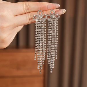 Dettaglio di orecchini a fiocco in argento con lunghe nappe di strass brillanti