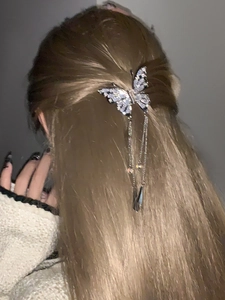 Detail showing a silver butterfly hair claw with tassel on long dark brown hair
