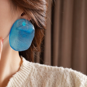 Close-up of large blue acrylic irregular chip earring on model with professional lighting
