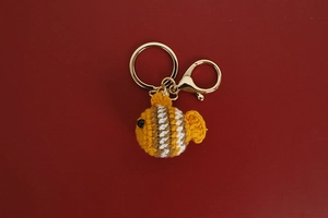 Detailed view of handmade crochet clownfish keychain with golden metal clasp accessory