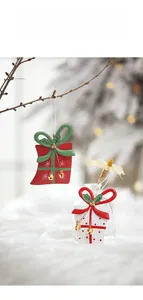 Close-up of red and white metal gift box ornaments with gold bells for Christmas tree