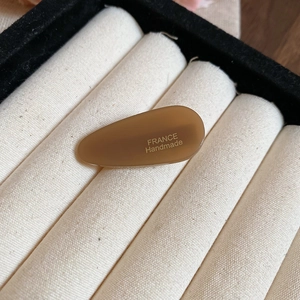 Gros plan sur la pince à cheveux goutte en acrylique marron caramel avec marquage doré