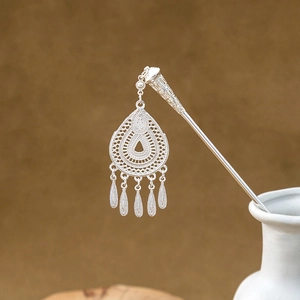 Detailed close-up of a silver hollow hair pin with elegant leaf tassels and water drop shape