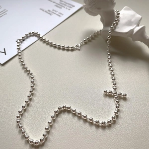 Macro shot of silver beaded chain necklace with cross pendant on display model
