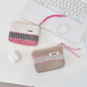 Macro shot of knitted stripe cosmetic bag with metal zipper and lifestyle props