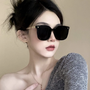 Fashionable oversized square sunglasses with black lenses and gold chain temples