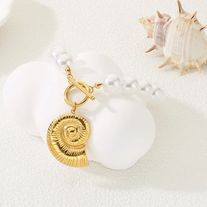 Close-up of pearl bracelet with golden seashell pendant and OT clasp on a white stand