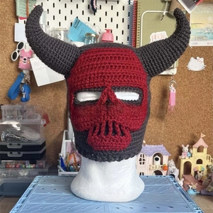 Detail of handmade crochet balaclava with horn design and red-grey skull patterns