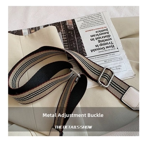 Close-up of adjustable wide canvas shoulder strap with classic stripe pattern and metal buckle