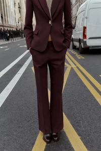 Détail d'un tailleur pantalon bordeaux pour femme avec col en V et bouton métallique