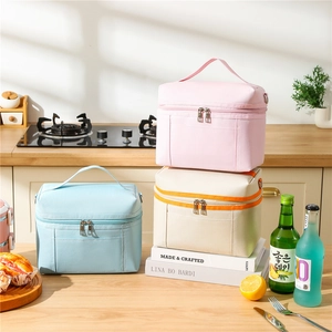 Three assorted insulated lunch bags with oxford fabric handles in a home kitchen setting