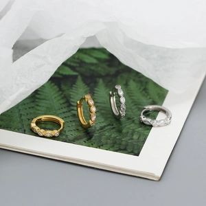 Detailed view of silver and gold paved hoop earrings placed on a lifestyle magazine