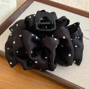 Polka dot fabric hair claw clip in black satin with an elegant bow design for women