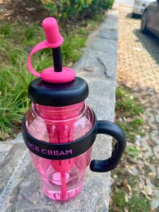 Detailed view of pink plastic tumbler with black handle, straw and ICE CREAM text