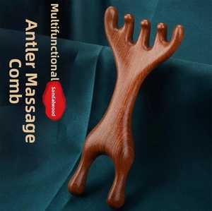 Macro detail of sandalwood deer-shaped scalp massage comb on dark green fabric