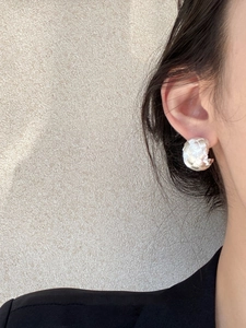 Close-up of silver C-shaped hoop earring with textured wrinkle finish on model ear