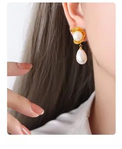 Detailed view of gold irregular wave earrings with white round and teardrop pearls