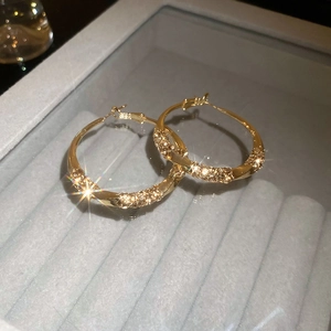 Detail of twisted gold hoop earrings with sparkling crystals in a velvet jewelry box