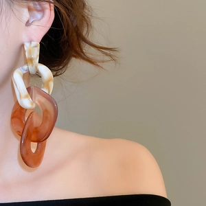 Model wearing acrylic marble resin earrings with three interlocking rings and tortoiseshell pattern