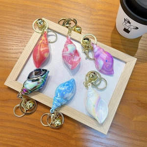 Colorful marble conch shell keychains with bells displayed in a wooden frame