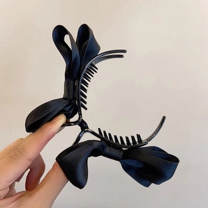 Close-up of a large black satin bow hair claw clip with durable plastic teeth