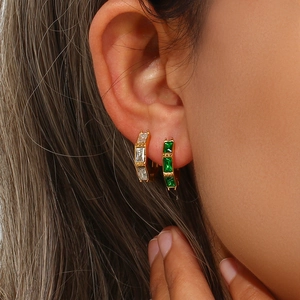 Detailed view of bamboo style gold hoop earrings with white and green rectangular zircons