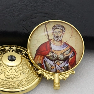 Detailed view of a golden Orthodox saint icon badge with vibrant colors and ornate metal stand