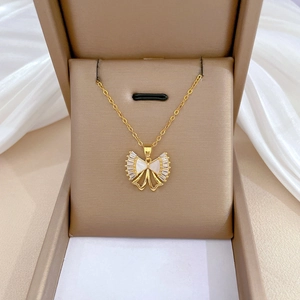 Detail of gold bow necklace featuring white shell inlay and sparkling pavé zircons