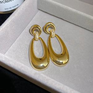 Detailed view of polished gold oval earrings with zircon inlay in a jewelry box