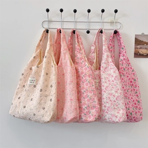 Detail of five pink floral cotton tote bags with bear patterns hanging on wall hooks