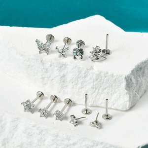 Detailed macro view of silver labret piercings with butterfly and scorpion designs